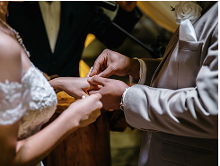 Close-up of a bride and groom exchanging rings during their wedding ceremony.